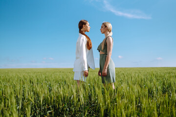 Two Beautiful posing  woman in the green field.  Fashion, style concept.