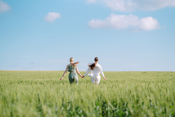 Two Beautiful posing  woman in the green field.  Fashion, style concept.