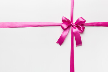 Top view of purple ribbon rolled and pink bow isolated on colored background. Flat lay with copy space