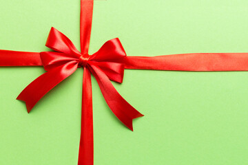 Top view of Red ribbon rolled and red bow isolated on colored background. Flat lay with copy space