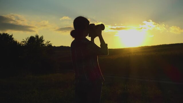 A young woman photographs the sun at sunset. The girl is filming the sunset. Camera movement. The concept of happiness, hobby, relaxation.
