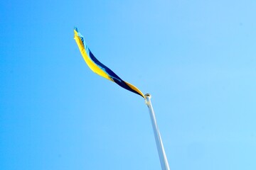 Schwedische Flagge im Wind vor strahlend blauem Himmel.