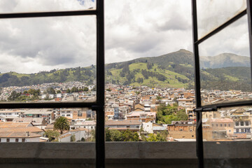 Fototapeta na wymiar through a window the landscape of the city of Quito-Ecuador in Latin America, architecture with mountains in the background and sky with clouds
