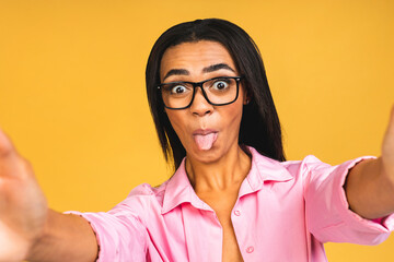Young funny african american black casual woman grimacing and making selfie on smartphone isolated...