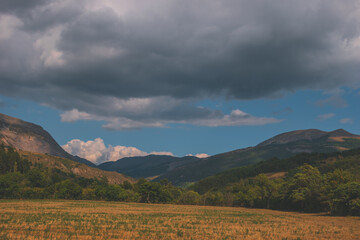 A picturesque landscape view of the French Alps mountains and grass field slash farmland