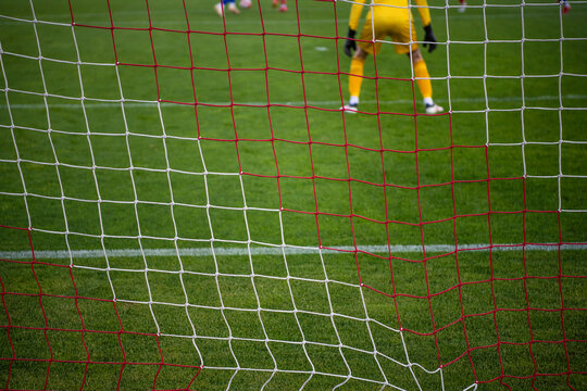 Football goal net during the game. Blurred players in background. Soccer background blurred photo, focus on net.