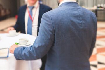 Group of men in business suits talking and discussing during coffee break at conference, politicians and entrepreneurs networking and negotiate, businessmen have a conversation
