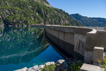 Obraz na płótnie Canvas mountain reflection in still blue water lake, long concrete Barrage Da, Lac de Cap-de-Long reservoir high amongst Pyrenees mountains in France