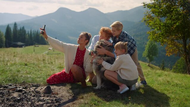 Family taking selfie mountain hill sitting with husky. Woman making happy photo.