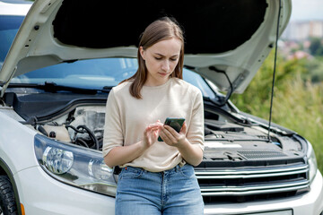 Young woman opening bonnet of broken down car having trouble with her vehicle. Worried woman...