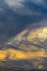 A distant airplane approaches landing below clouds at sunset, above Rio de Janeiro, Brazil