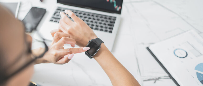 Female employee uses smartwatch in office workplace
