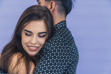 Young woman with dark long hair smiling hugging her boyfriend leaning on his shoulder. Happy couple. Studio shot. High quality photo