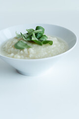 Healthy vegan cauliflower cream soup with herbs in white bowl