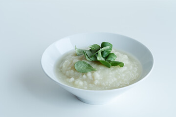 Healthy vegan cauliflower cream soup with herbs in white bowl