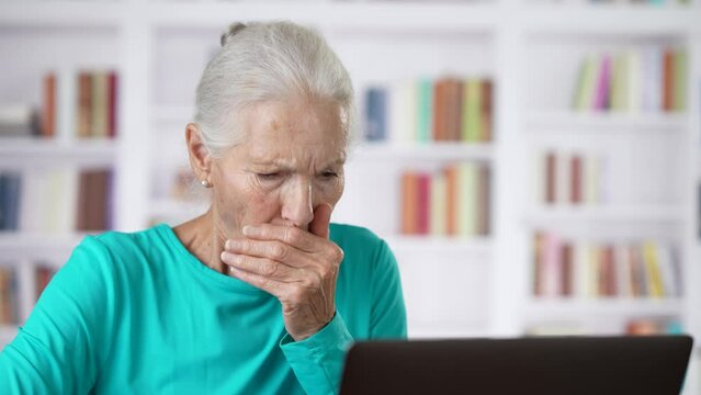 Elderly woman sick coughing at home office talking to doctor on laptop in online consultation video call use webcam.