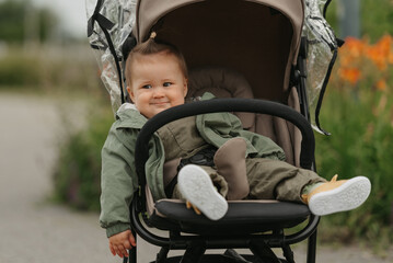 A female toddler is sitting in the stroller on a cloudy day.