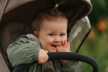 A female toddler is sitting in the stroller on a cloudy day.