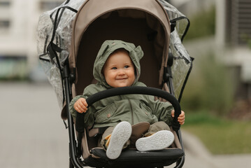 A female toddler is sitting in the stroller on a cloudy day.