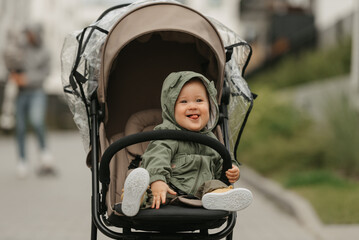 A female toddler is sitting in the stroller on a cloudy day.