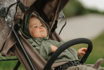 A female toddler is sitting in the stroller on a cloudy day.