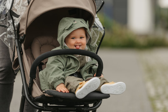 A female toddler is sitting in the stroller on a cloudy day.