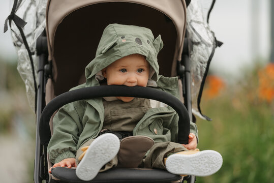 A female toddler is sitting in the stroller on a cloudy day.