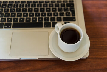 coffee cup on a laptop on a wooden table