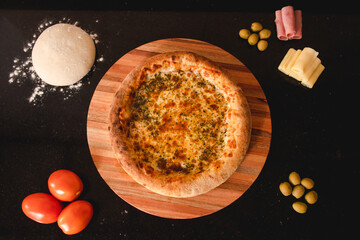 Top view of a mozzarella pizza with stuffed border on a black table.