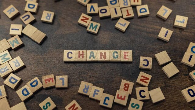 CHANGE. Scattered wooden square letter puzzles on a dark wooden table. Advertisement concept. High quality 4k footage