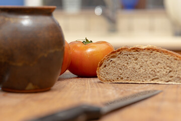 wooden board with a tomato and an artisan bread cut in half. rustic scene