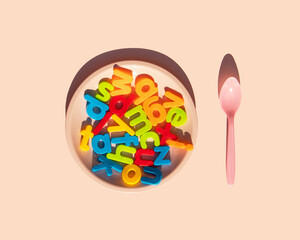 Minimalistic education idea. Creative back to school concept. Colorful composition with letters, plate and spoon on pastel bright pink background.
