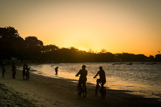 Sunset on the beach with cyclist couple at Buzios town, State of Rio de Janeiro, Brazil. Taken with Nikon D7100 18-200 lens, at 50mm, 1/1600 f 9.0 ISO 125
