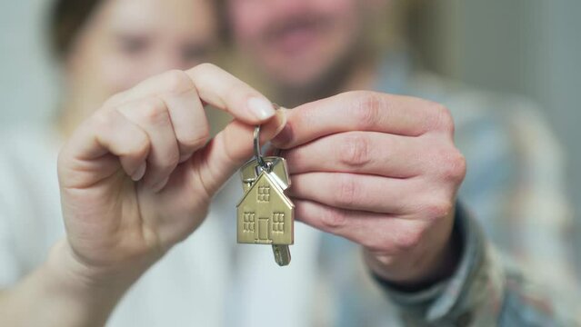 close up of the hands happy married couple holding keys to a new apartment. family bought a house together, hugging and looking at camera. concept of buying a home, loans, dwelling. Closeup