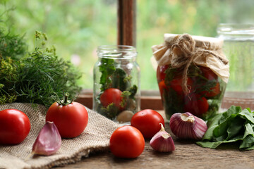 Glass jars, fresh vegetables and herbs on wooden table indoors. Pickling recipe