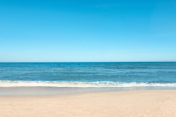 Fototapeta na wymiar Blurred view of beautiful sea and sandy beach on sunny day