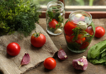 Glass jars, fresh vegetables and herbs on wooden table indoors. Pickling recipe