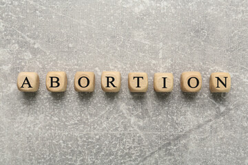 Word Abortion made of wooden cubes on grey background, flat lay