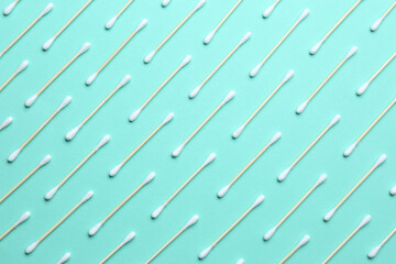Many cotton buds on turquoise background, flat lay