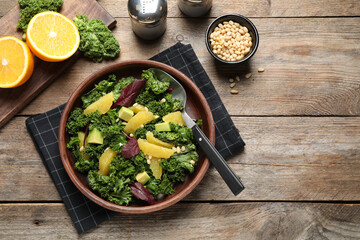Tasty fresh kale salad on wooden table, flat lay