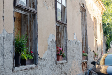 Fototapeta na wymiar Facade of an ancient building.Beautiful flowers on the windowsill.