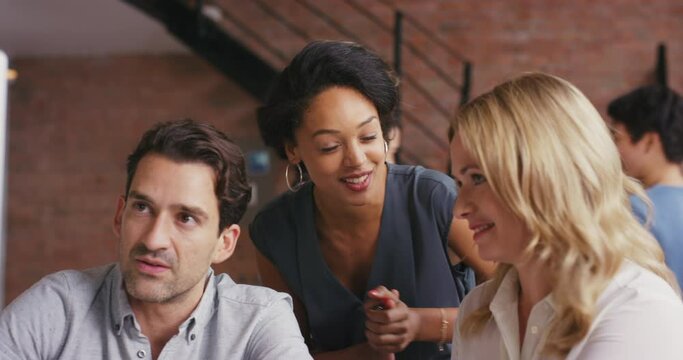 Excited, diverse and happy colleagues talking about a project in a busy office or agency. Team of joyful employees working on a business proposal together and collaborating for success