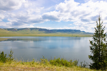 Fototapeta na wymiar Landscape. Lake from a height among the green mountains against the backdrop of a cloudy sky. Lake Maloe, Siberia, Krasnoyarsk Territory, Russia