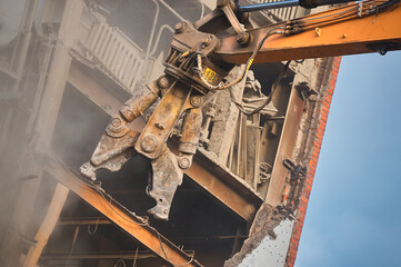 Hydraulic cutter of crane demolishes old industrial building