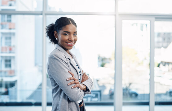 Confident, happy and ambitious woman with standing with her arms crossed and showing good leadership skills in a modern office. Portrait of a smiling business intern ready for a successful future