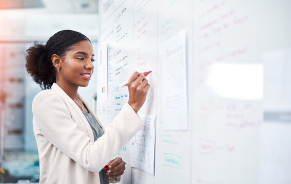Project manager writing on a whiteboard to plan ideas and visualize business strategy. Focused, confident and thoughtful businesswoman showing ambition and dedication while working in an office