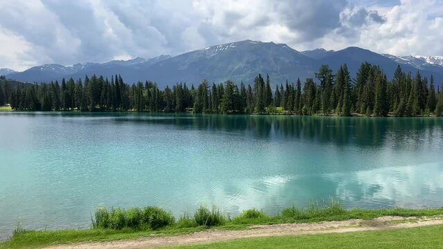 View of Beauvert Lake at Jasper, Alberta,Canada in a summer. The pristine alpine lake is surrounded by forest with mountain peaks in the distance. 