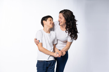mother and son hug, communicate. models in white t-shirts, blue jeans. White background