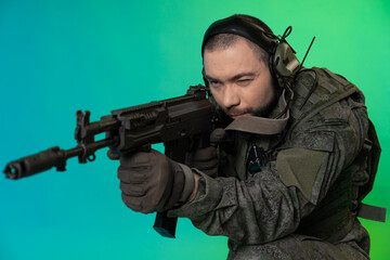 soldier in the studio on a green background with colored light. a man in military uniform with a...