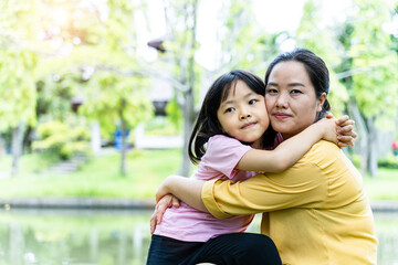 Naklejka premium Cute young daughter with her mother hugging in love playing together in a park